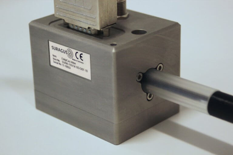 Product photo of a laying EddyCus® inline R ringsensor for slurry, paste and fluid monitoring with a test tube